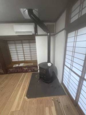 カフェ板張り漆喰壁のリビングに鎮座するのはゴツい薪ストーブ。