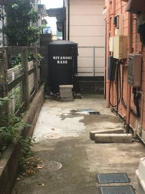 裏手の奥に勝手口（実質的な入口とバイク洗い場）あり。