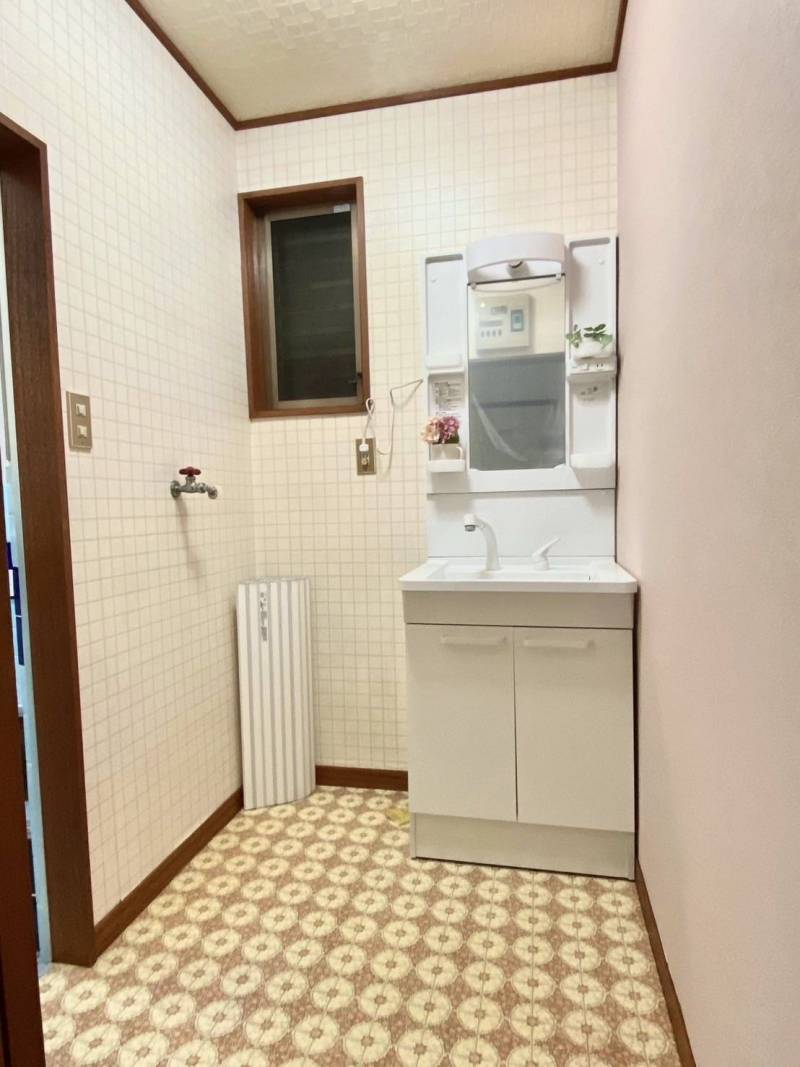 洗面所。新設の洗面台にも拘りの優しいピンクの壁紙にもご注目。