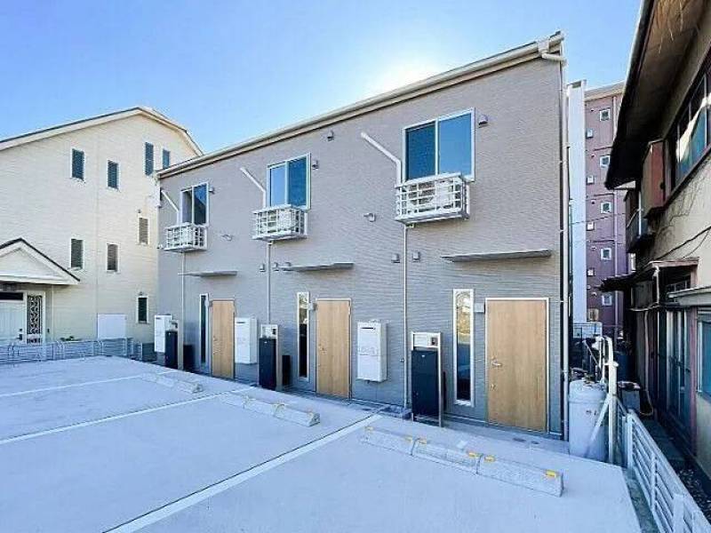 落ち着いたグレーの外壁に木目のドアが目を引くシンプルな外観