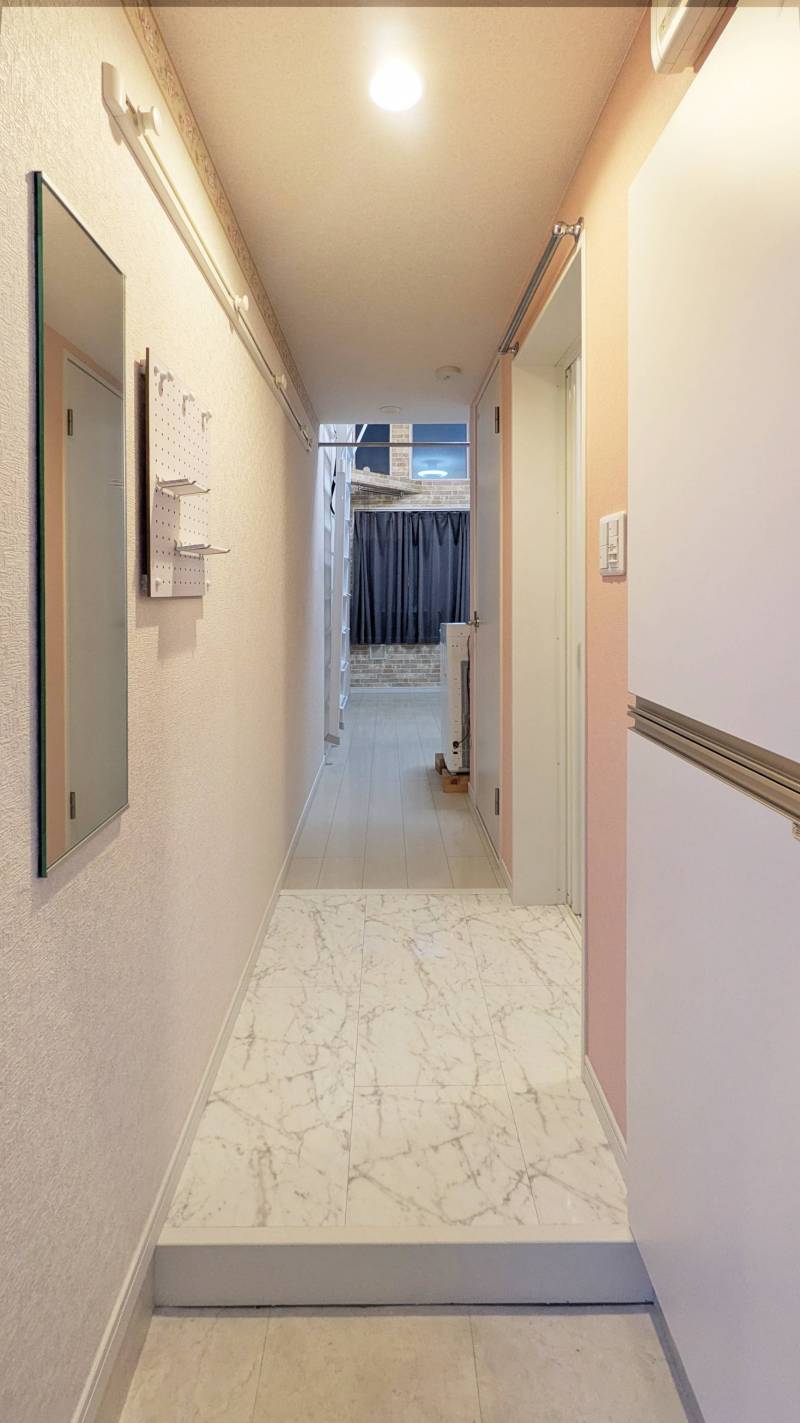 玄関入ってすぐ．鏡，有孔ボード，コート掛けが便利．