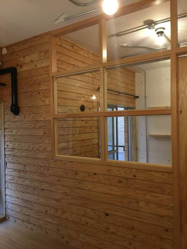 寝室とリビングの間のウッド壁にはガラス窓が入り開放感あり